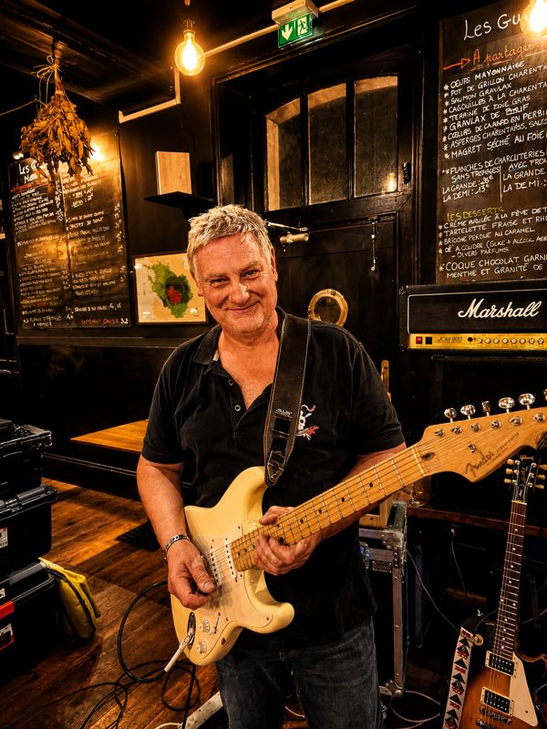 Alambic Brothers — Guitariste souriant avec sa guitare blanche