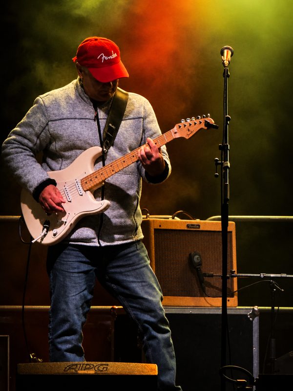 Alambic Brothers — Guitariste à casquette rouge sous les projecteurs